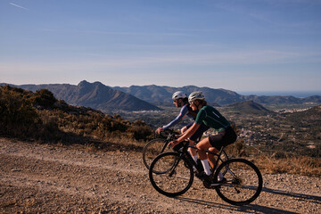 Two cyclists are riding along a scenic mountain gravel route.Cyclists are practicing on gravel...