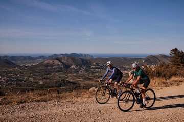 Gravel adventure.Two cyclists are riding along a scenic mountain gravel route.Cyclists are practicing on gravel road.Beautiful sunny day for cycling.Spain.