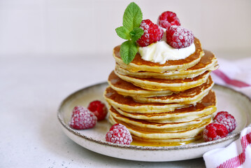 Delicious homemade pancakes with whipped cream, maple syrup and raspberry for a breakfast.