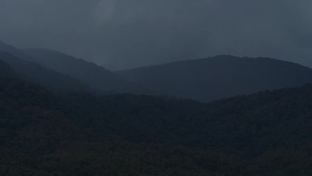 Fast speed closeup b-roll scene of hard rainstrom over the mountain with gloomy cloudy sky, heavy rain pouring in a valley, bad weather with dark raincloud in rainy season