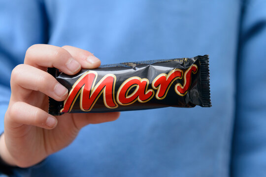 Close-up of a child's hands holding a candy bar from the brand Mars.
