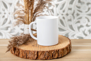 Obraz na płótnie Canvas One white color empty mug mock up in home room. Single cup on wood table with dry reed plant decoration. Lot of empty copy space. 