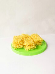Raw dry yellow noodles served with green plate isolated on white background