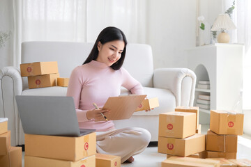 Entrepreneur, small business, SME, freelance woman working from home with lots of boxes on the side.