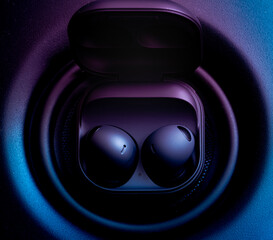 black wireless earpone buds on speakers background