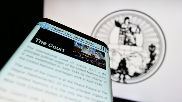 Stuttgart, Germany - 04-23-2023: Mobile phone with webpage of the International Court of Justice (ICJ) on screen in front of logo. Focus on top-left of phone display.
