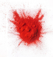 Top view of splashing paprika red color powder pile over double white surface.