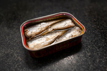 Selective focus on a brilliant oiled sardines tin can against black marble
