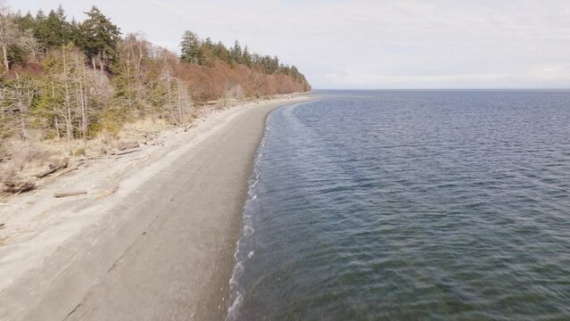 A gulf island in British Columbia Canada. A small island on the west coast of BC called Denman Island, showing the beach and ocean next to trees.
