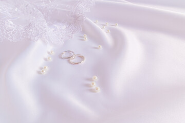 Luxurious white satin wedding background with two platinum engagement rings and a diamond. Layout...