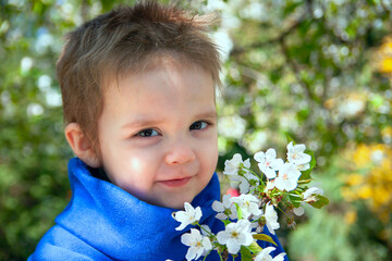 A sweet portrait of a toddler looking at the camera, surrounded by flowering plants and filled with innocence.