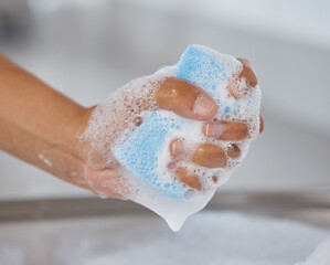 Time to tackle the dirty dishes. Closeup shot of an unrecognisable woman squeezing soap from a sponge at home.