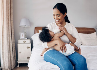 Youre my pride and joy. Shot of an attractive young woman sitting on the bed at home and feeding her baby daughter with a bottle.
