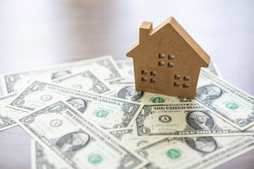 Wooden house on a stack of dollar money banknotes. Property loan concept