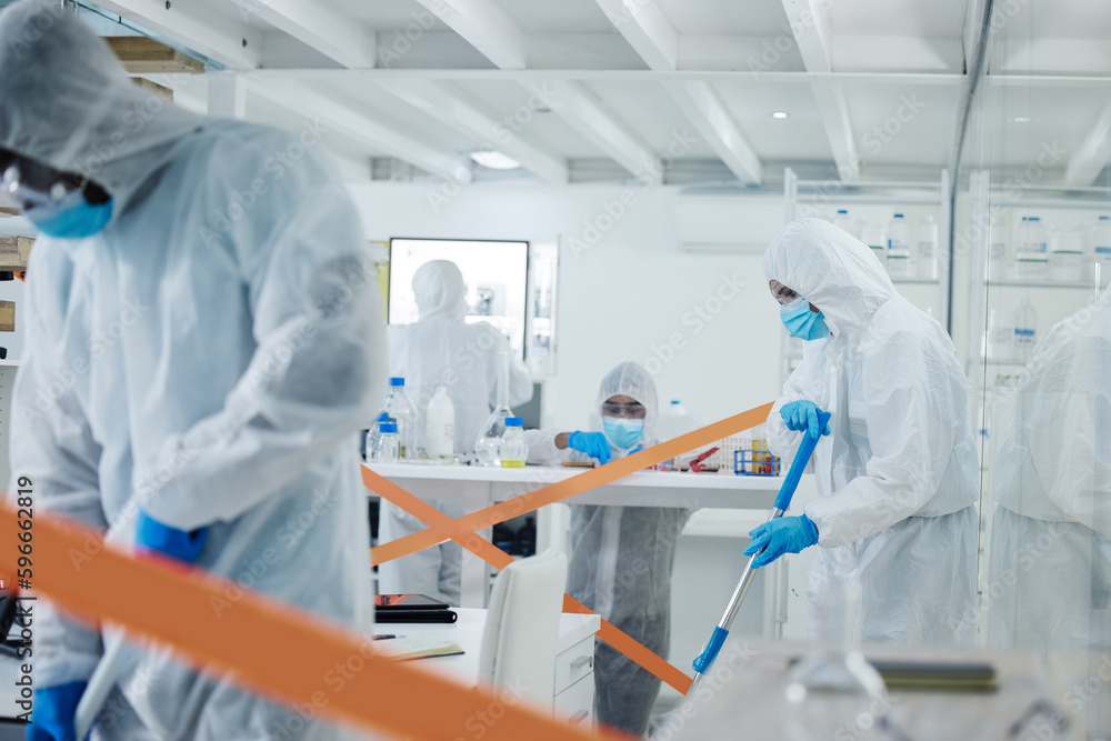 Poster Cleaning up is a team effort. Shot of a group of scientists cleaning up a mess at a lab.