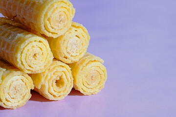 Yellow lemon waffles in the shape of a tube close-up.
