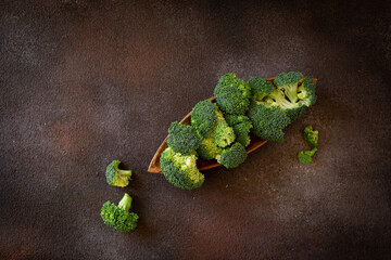 Fresh broccoli the brown cutting board on dark brown background 