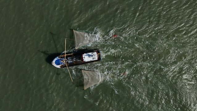 Top down aerial over fishing trawler cruising in North Sea followed by seagulls