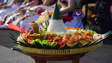 Nasi tumpeng (cone rice) served with urap-urap (Indonesian salad), fried chicken and noodles. Nasi...