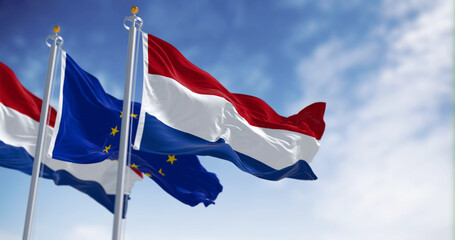 Naklejka na ściany i meble Netherlands and EU flags waving in the wind on a clear day