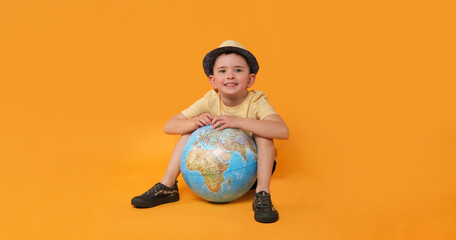 Little boy with globe on orange background.