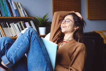 Young happy woman reading and relaxing at home during leisure time.