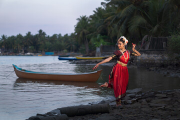 A beautiful Indian Bharatanatyam dancer performing near a beach - obrazy, fototapety, plakaty
