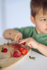 Little boy eating strawberries by himself