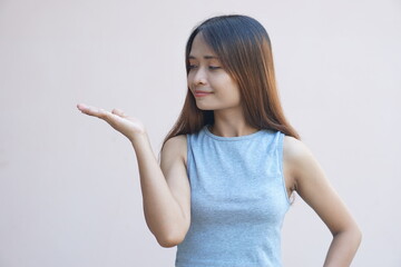 Asian woman extending her hand to the side like holding a product
