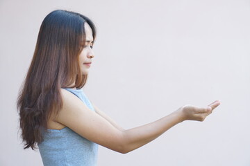 Asian woman extending her hand to the side like holding a product