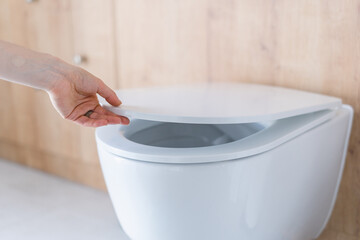 Woman closing the lid of a toilet seat
