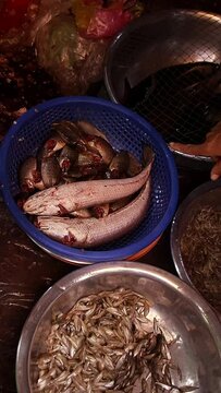 Overhead view of seller and buyer bargaining over the price of live Channa striata or striped snakehead fish at the local wet market Samaki in Kampot Cambodia, candid authentic daily life