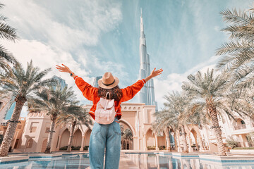 Fototapeta From behind, you can see the traveler girl arms spread wide as she take in the incredible view of the Burj Khalifa and the Dubai skyline. obraz