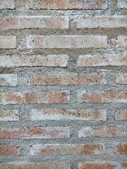 background of exposed brick wall in red earth color with a thin layer of natural white from the passage of time with a cement seam