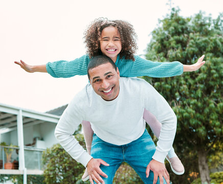 Look No Hands. Shot Of A Man Carrying His Daughter On His Back While Playing Outside.