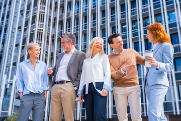 Cheerful group of coworkers outdoors in a corporate office area, middle-aged businesswoman and businessman