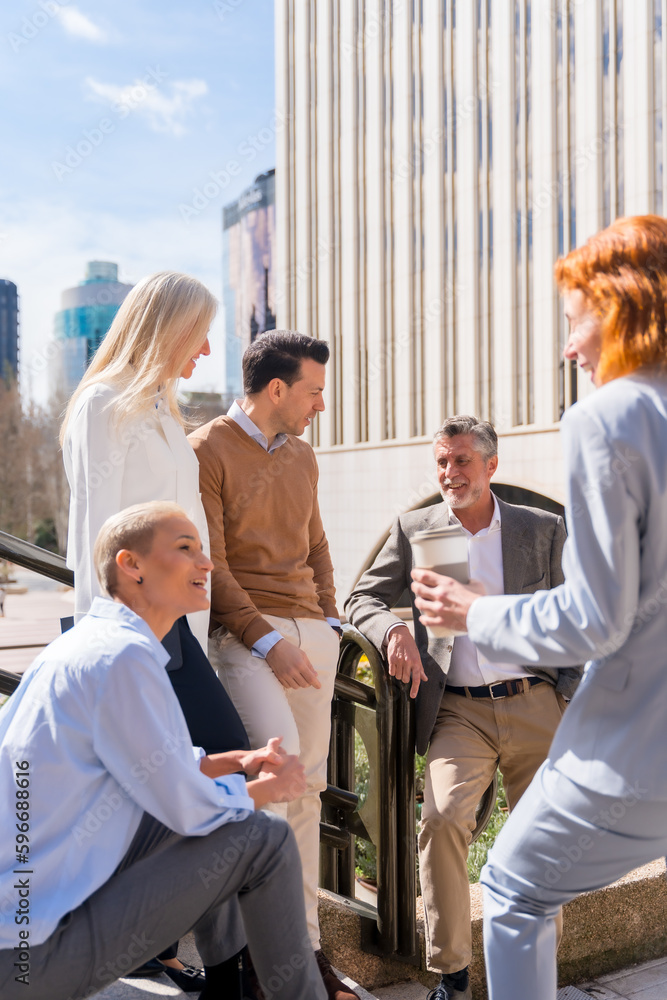 Wall mural Cheerful group of coworkers outdoors in a corporate office area resting