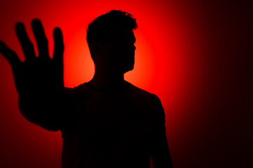 silhouette of a man on a red background with a stop hand gesture