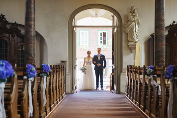 Photosession of stylish wedding couple on catholic church.