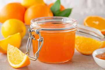 Orange marmalade or orange jam in glass jar with fresh fruits on a gray background. Copy space.