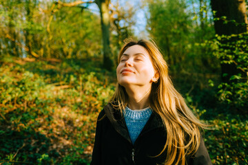 Attractive caucasian woman breathe fresh air , enjoying springtime on a sunset in natural parkland