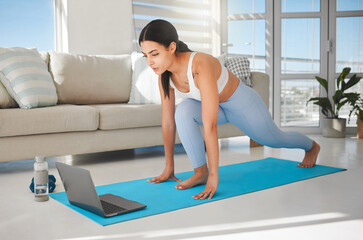 Starting another session online with her personal trainer. Shot of a sporty young woman using a laptop and doing lunges while exercising at home.