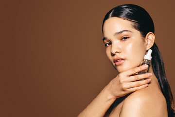 Using female cosmetic products for healthy skin: Portrait of a confident young woman holding face...