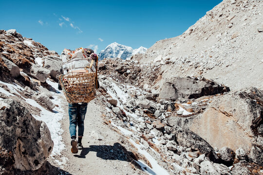 Nepalian Porter carrying heavy load on his back to Everest Base camp. Himalayas. Nepal.