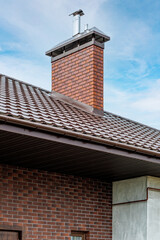 A chimney or ventilation pipe in a private house made of decorative bricks on the roof