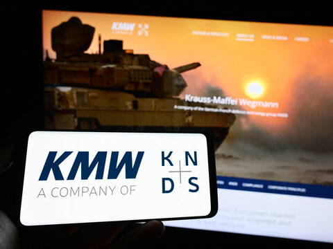 Stuttgart, Germany - 04-25-2023: Person holding mobile phone with logo of Krauss-Maffei Wegmann GmbH Co. KG (KMW) on screen in front of business web page. Focus on phone display.