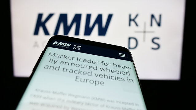 Stuttgart, Germany - 04-25-2023: Mobile phone with website of Krauss-Maffei Wegmann GmbH Co. KG (KMW) on screen in front of business logo. Focus on top-left of phone display.