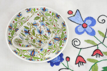 Cup with a traditional, regional pattern on a tablecloth with ethnic, traditional embroidery from Kashubia in Poland. - obrazy, fototapety, plakaty