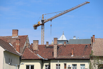 Fototapeta na wymiar House roofs with smoke stacks and a tower crane in the background