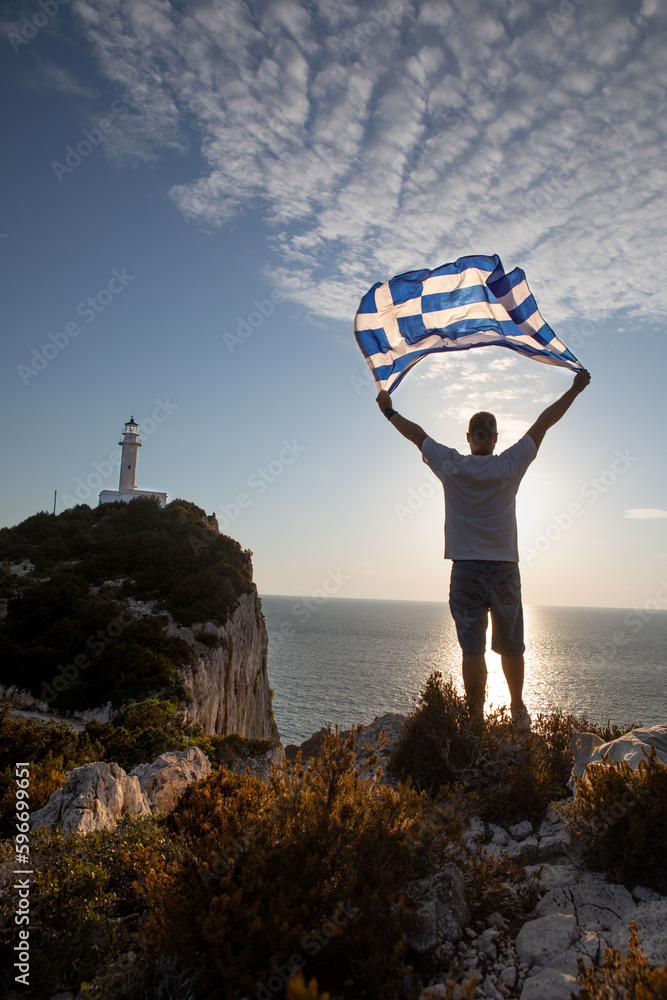 Wall mural man with greece flag looking at sunset above the sea